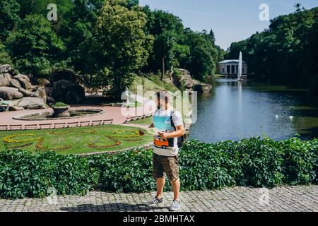 Sofia Park, Ukraine. Schöner Mann mit Bart in einem dendrologischen Park. Mann mit Rucksack auf dem Hintergrund des Sees mit einem Brunnen und einem weißen Stockfoto