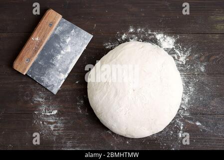 Prozess der Vorbereitung von frischen natürlichen Hefeteig für die Gesundheit hausgemachtes Brot mit Schaber für Teig auf einem gark braunen Holzhintergrund, kopieren Raum. Schritt für Schritt Stockfoto