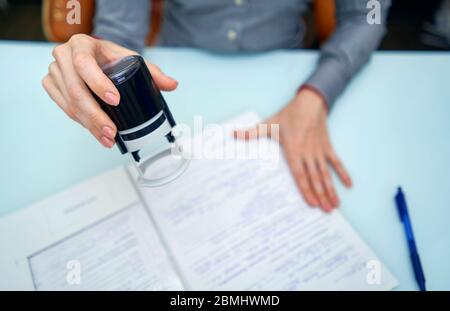 Kleines Mädchen setzt einen Stempel auf Dokumente Stockfoto