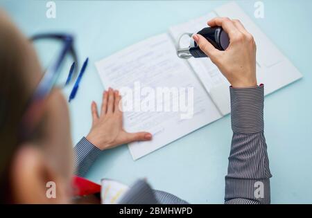 Kleines Mädchen setzt einen Stempel auf Dokumente Stockfoto