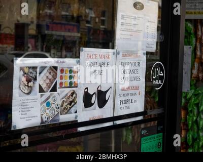 London. GROSSBRITANNIEN. Mai 2020 um 14 Uhr. Nahaufnahme der Business-Haustür in Bethnal Green mit Gesichtsmaske verfügbar Hinweis und Social Distancing Info. Stockfoto