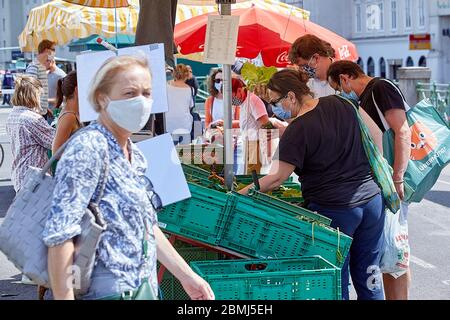 Wien, Österreich. Mai 2020. Menschen mit Gesichtsmasken kaufen am 9. Mai 2020 auf einem Wiener Straßenmarkt ein. Österreich hat seine Beschränkungen nach einer fast zweimonatigen Lockdown zur Bekämpfung des Coronavirus schrittweise gelockert. Bisher haben alle Shop mit den Maßnahmen, die einen sicheren Abstand halten, tragen Masken und so weiter beim Einkaufen wiedereröffnet. Kredit: Georges Schneider/Xinhua/Alamy Live News Stockfoto