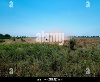 Der Mähdrescher entfernt die Gerste auf dem Feld und stäubt hart. Stockfoto