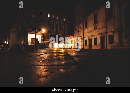 Dunkle Nachtstraßen mit heller, erleuchteter Terrasse eines Restaurants in Venedig, Italien Stockfoto
