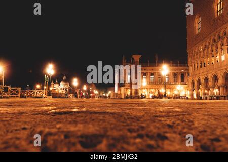 Bewegung verschwommen Touristen, die entlang der Piazza riva degli Schiavoni entlang historischer Gebäude in der Nacht mit hellen Laternen in Venedig, Italien Stockfoto