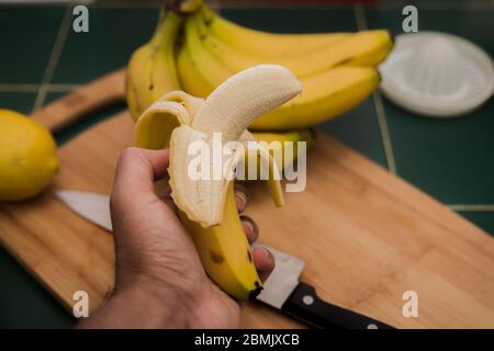 Banane in der Hand eines Mannes geschält Stockfoto