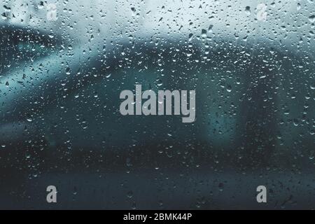 Regentropfen auf Glas. Blick durch das Autofenster. Starker Regen. Abstrakter Hintergrund mit Tröpfchen auf transparenter Oberfläche Stockfoto