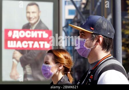 Menschen, die Gesichtsmasken tragen, gehen vorbeugend an einer Plakatwand vorbei, auf der ein Foto von Vitali Klitschko, dem ehemaligen Schwergewichtsmeister und heutigen Bürgermeister von Kiew, zu sehen ist.Diese Schrift steht auf Stop Hängen Around ruft die Menschen auf, zu Hause zu bleiben, um sich vor dem Coronavirus zu schützen.wie am 09. Mai, 2020 das ukrainische Gesundheitsministerium verzeichnete seit Beginn des Coronavirus Covid-19-Ausbruchs insgesamt 14,710 bestätigte Fälle und 376 Todesfälle. Ministerkabinett der Ukraine haben die Coronavirus-bezogene Quarantäne im Land bis zum 22. Mai 2020 verlängert, aber ab Mai 11 sind einige Quarantänebeschränkungen geplant, r zu sein Stockfoto