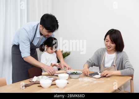 Junge asiatische Mutter und Papa Herstellung Knödel mit Tochter Stockfoto