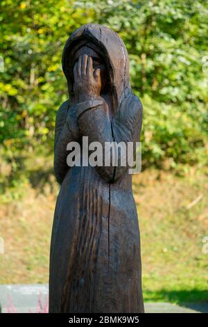 Eine traditionelle Holzskulptur, die von Hand geschnitzt wird, markiert ein Grab. Auf dem Friedhof Antakalnis in Vilnius, Litauen. Stockfoto