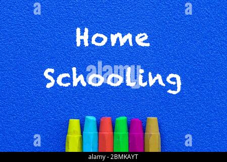 Homeschooling. Wörter oder getippter Text auf blauer Platine. Mehrfarbige Buntstifte. Draufsicht. Konzept der frühen Ausbildung. Stockfoto