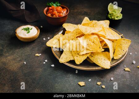 Mexikanische Mais-Chips Nachos und Satz von traditionellen Dips, Kopierraum. Tortilla oder Nacho Chips mit Saucen für den Snack. Stockfoto