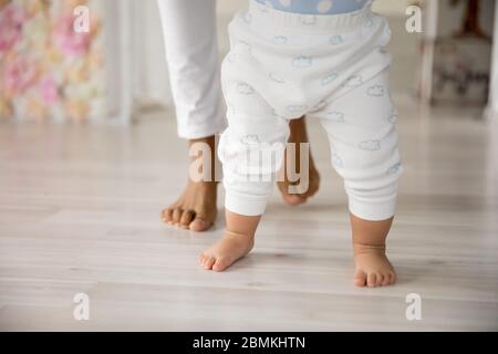 Nahaufnahme von kleinen Baby machen erste Schritte mit Mama Stockfoto