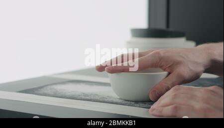 Mann Hände Sand Boden der weißen Keramikschale Stockfoto