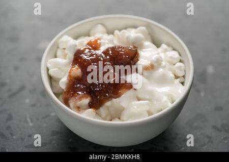 Quark mit Feigenmarmelade in weißer Schüssel auf Beton Hintergrund Stockfoto