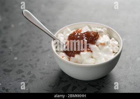 Quark mit Feigenmarmelade in weißer Schüssel auf Beton Hintergrund Stockfoto