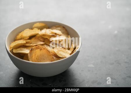 Kartoffelchip leicht mit schwarzem Pfeffer in einer weißen Schüssel bestreut Auf konkretem Hintergrund mit Kopierraum Stockfoto