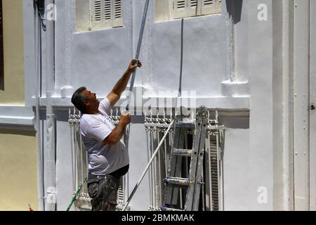 Männer bei der Arbeit, die Außenwand eines Hauses in Weiß malen - Athen, Griechenland, 6. Mai 2020. Stockfoto