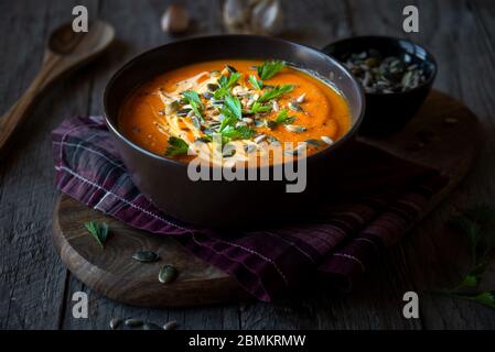Kürbissuppe mit Sahne, Petersilie und Kürbiskernen auf dunkel Stockfoto