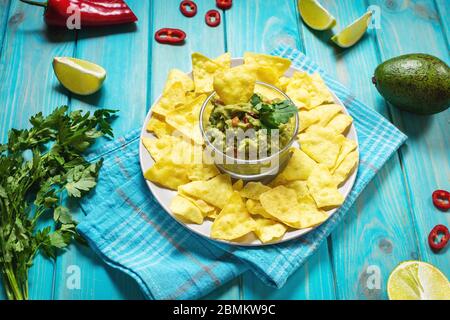 Nachos. Tortilla Chips mit Guacamole auf blauem Holzhintergrund. Stockfoto