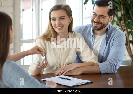 Makler geben Schlüssel zu aufgeregt paar bewegen zusammen Stockfoto