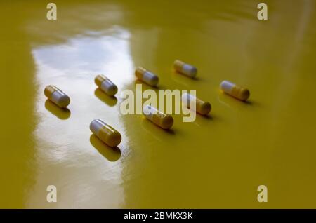 Gelbe und weiße Kapseln und weiße Pillen auf gelbem Hintergrund. Stockfoto