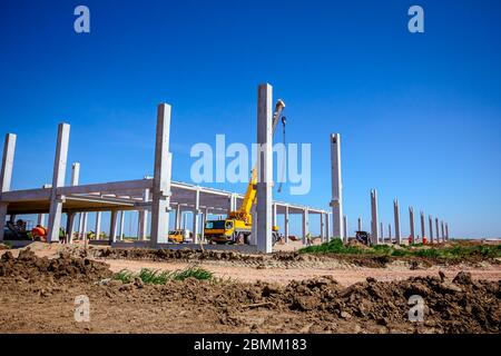 Montage einer riesigen Beton Skelett der industriellen Gebäude mit Maschinen, Menschen arbeiten. Blick auf die Baustelle. Stockfoto