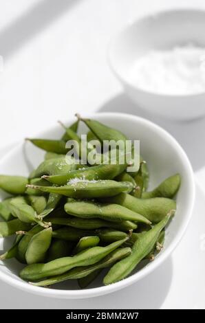 Bio Edamambohnen Snack in Schüssel auf dem Tisch mit Meersalz Stockfoto