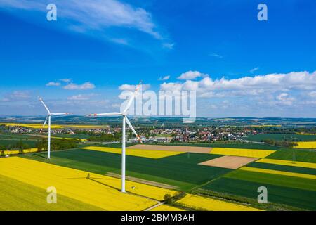 Luftaufnahme von Windenergieanlagen. Raps blüht. Windmühlen und gelbe Felder von oben. Landwirtschaftliche Felder an einem Sommertag. Erneuerbare Energien. Stockfoto