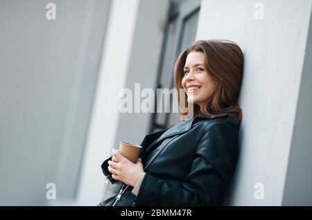 Junge lächelnde Frau, die auf dem Balkon Kaffee trinkt Stockfoto