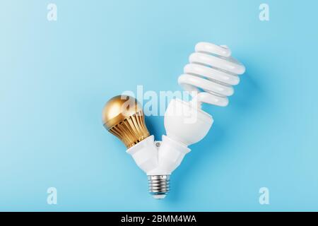 Gold LED-Glühbirne und energiesparend in einer doppelten Basis auf blauem Hintergrund. Die Aussicht von oben Stockfoto