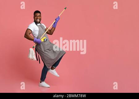 Funny African Man Mit Mop Griff Als Gitarre, Spaß Beim Reinigen Stockfoto