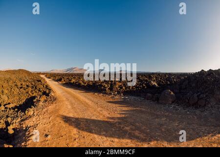 Luftaufnahme von Lavafeldern mit Straße und Vulkanen. Lanzarote, Kanarische Inseln. Stockfoto