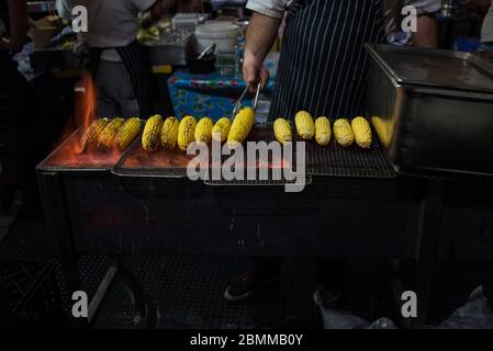 Melbourne, Australien - 14. Juni 2017: Person, die Maiskolben auf offenem Grill kocht. Queen Victoria Winter Nachtmärkte in Melbourne Stockfoto