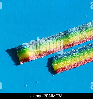 Natürliche Regenbogenfarben Marmelade Süßigkeiten auf dem blauen Hintergrund. Kopierbereich, leere Vorlage für Text Stockfoto