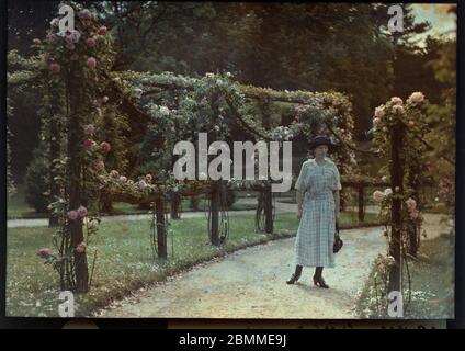 Portrait de femme de la bourgeoisie parisienne posant dans une allee bordee de rosiers au jardin de Bagatelle, Paris - (Dame aus der pariser Bourgeo Stockfoto