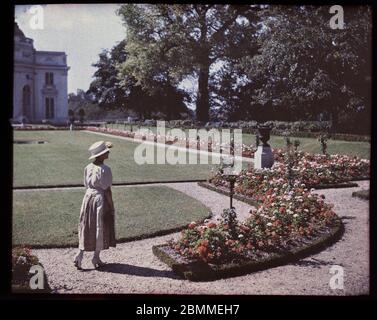 Portrait de femme de la bourgeoisie parisienne posant pres d'un parterre fleuri au jardin de Bagatelle, Paris - (Dame aus der pariser Bourgeoisie ne Stockfoto