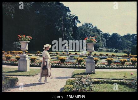 Portrait de femme de la bourgeoisie parisienne posant pres d'un parterre fleuri au jardin de Bagatelle, Paris - (Dame aus der pariser Bourgeoisie ne Stockfoto