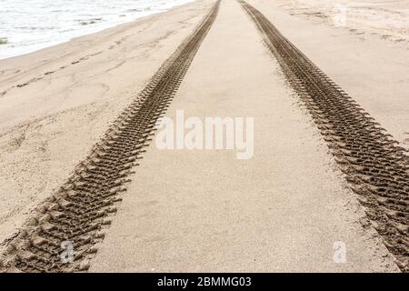 Nahaufnahme von Reifenspuren am Sandstrand. Stockfoto