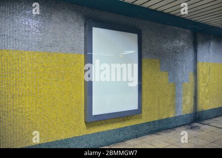 Leere weiße Plakatwand an einer schmutzigen und feuchten Wand an einem U-Bahnflur Stockfoto