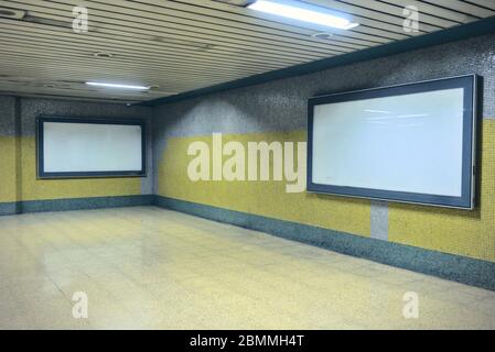 Zwei leere Werbetafeln an gelben und grauen Wänden auf den Korridoren der U-Bahn Stockfoto
