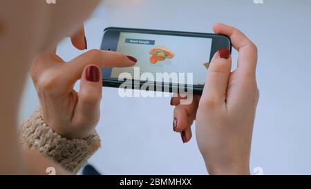 MOSKAU, RUSSLAND - 29. AUGUST 2018. Frau mit Smartphone mit Augmented Reality App und erkunden virtuelles Modell des Gehirns. Zukunft, Medizin und Stockfoto