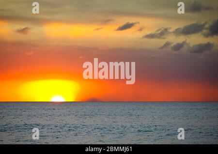 Die Insel Redonda, die zu Antigua & Barbuda gehört, mit einem roten Sonnenuntergang, der durch den Ascheregen des Montserrat-Vulkans erzeugt wird. Stockfoto