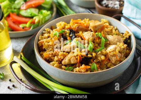 Bulgur Pilaf Nahaufnahme. Gesundes Essen Konzept. Bulgur mit Hühnchen, Gemüse und Pflaumen auf einer grauen Stein- oder Schiefer-Arbeitsplatte. Stockfoto