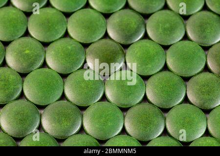 Nahaufnahme Hintergrund von vielen grünen Spirulina Tabletten aus kontrolliert biologischem Anbau gelegt In einer Schicht auf flacher Oberfläche Stockfoto