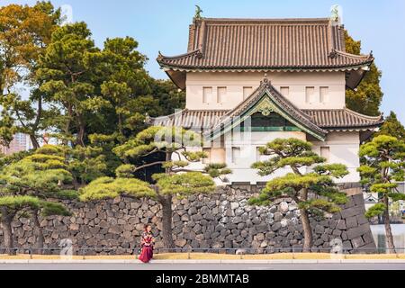 tokio, japan - märz 25 2020: Japanische Frau im Hakama Kimono vor dem riesigen Bergfried Edojō sakurada tatsumiyagura mit Gräben, die von Kiefern gesäumt sind Stockfoto