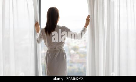 Rückansicht Frau steht in der Nähe von Fenster genießen Sie Stadtblick Stockfoto