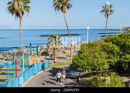 Zwei Frauen gehen in Phase 0 der Deeskalation während der Blockade des Covid 19 im touristischen Ferienort Costa Adeje auf dem Strandweg Playa Fanabe mit einem Hund spazieren Stockfoto