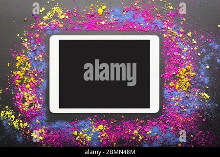 Touchpad auf bunten holi Pulver Hintergrund. Touchscreen-Computer auf festlichen holi Farben Hintergrund. Happy holi Festival Konzept Stockfoto