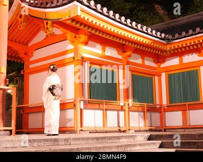 KYOTO, JAPAN - 06. NOVEMBER 2019: Eine junge Besucherin im Kimono am Tor des Yasaka Shrine oder Gion Shrine in Kyoto bei Nacht Stockfoto